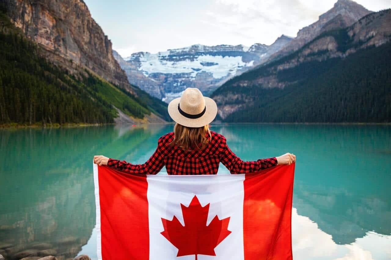 A woman wearing a checkered shirt holding the Canadian flag